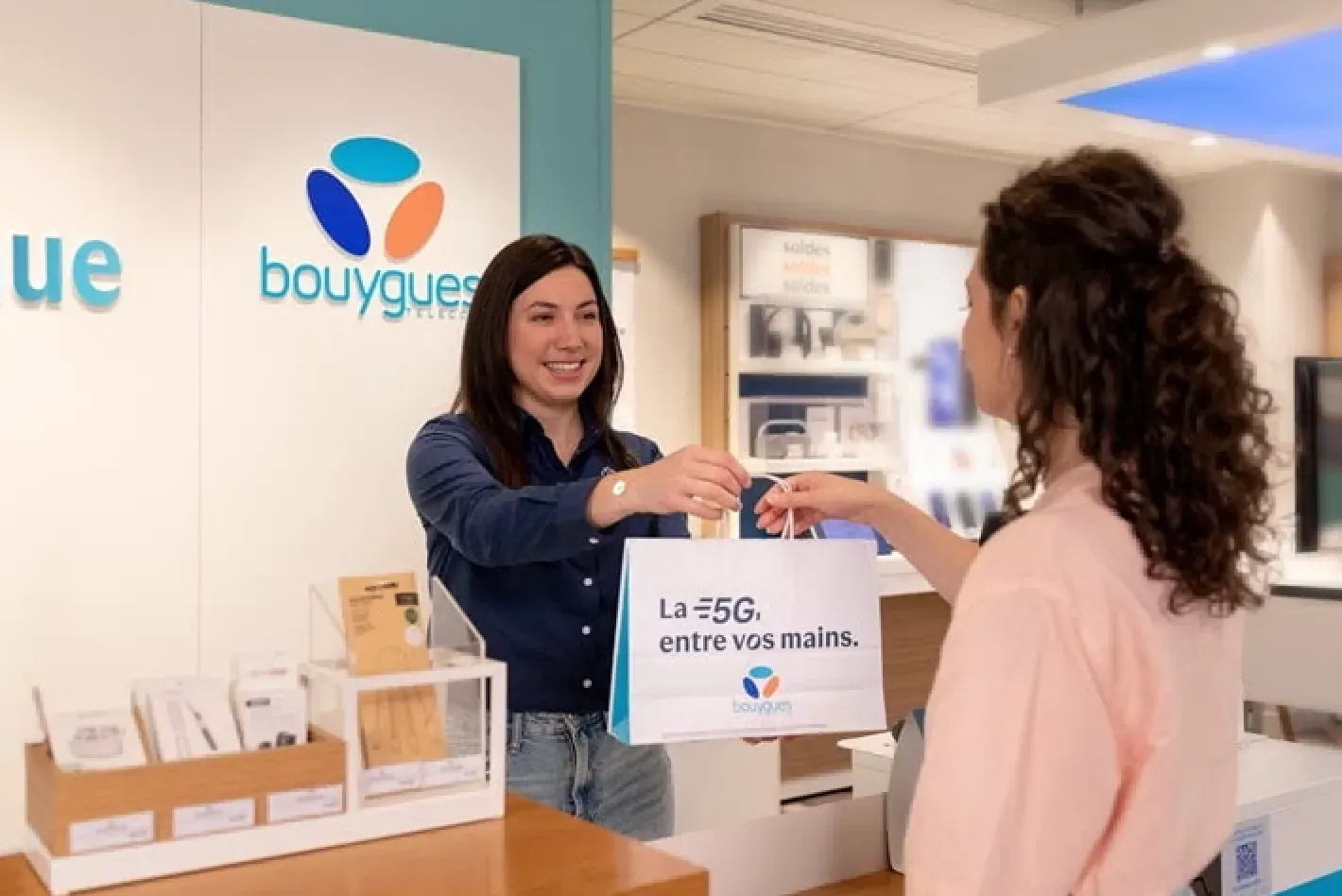 Conseiller de clientèle Bouygues Telecom en boutique, elle sourit à un client