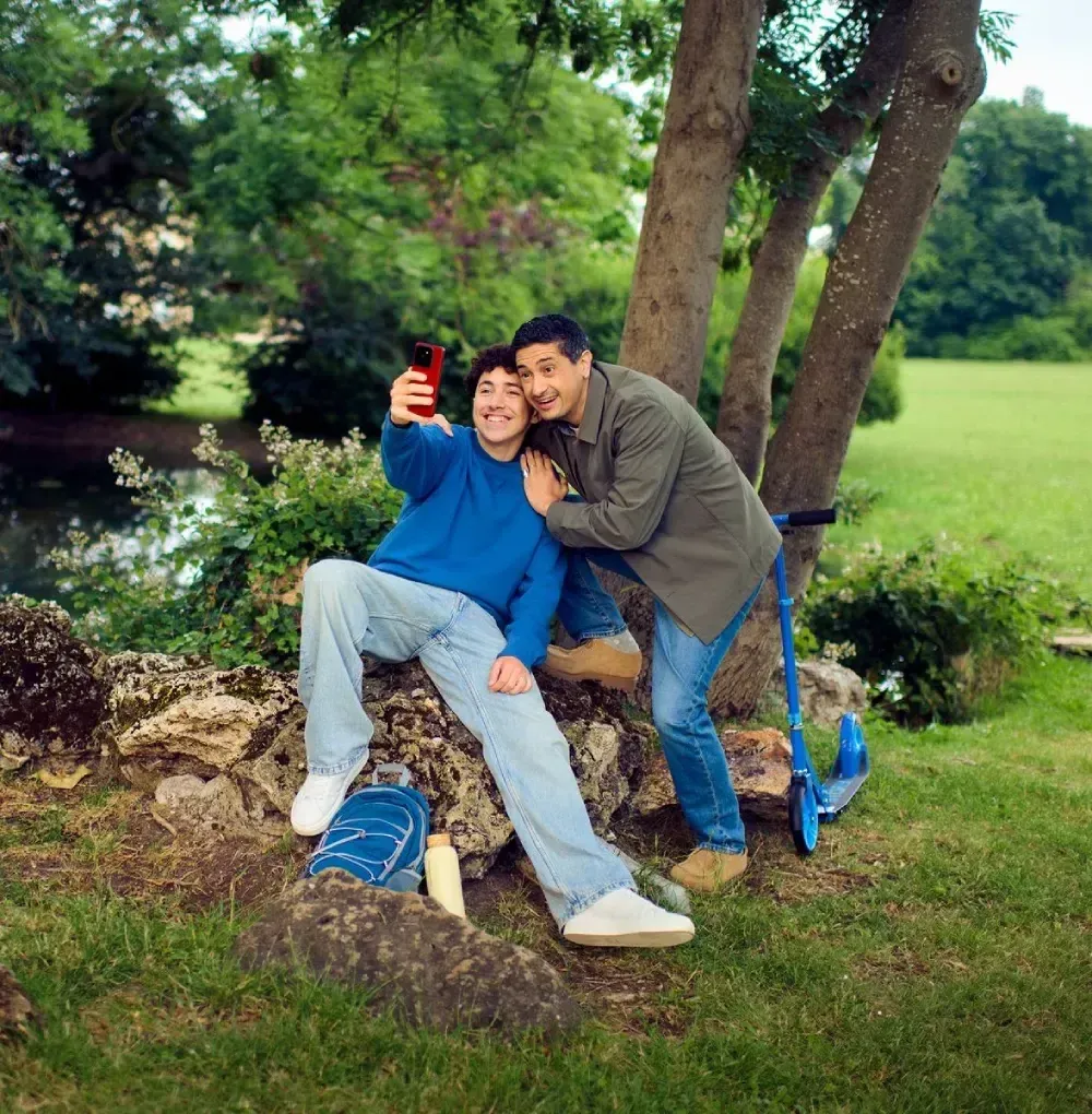 Un père et son fils se prennent en photo avec leur smartphone en fôret