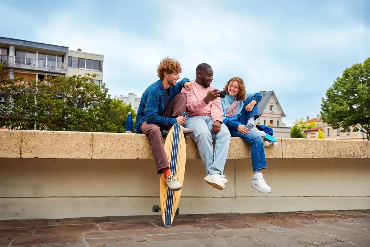 Groupe d’amis souriants devant leur smartphone, ils profitent du réseau Bouygues Telecom