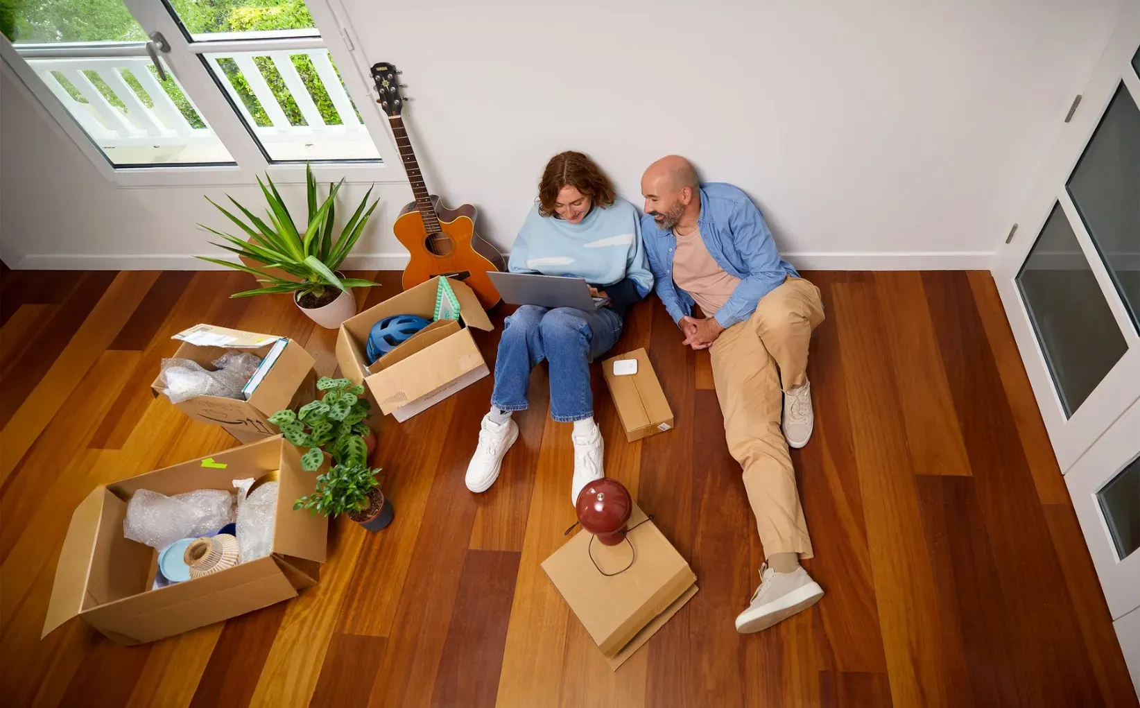 Deux amies devant leur ordinateur, on aperçoit des cartons de déménagement en arrière-plan