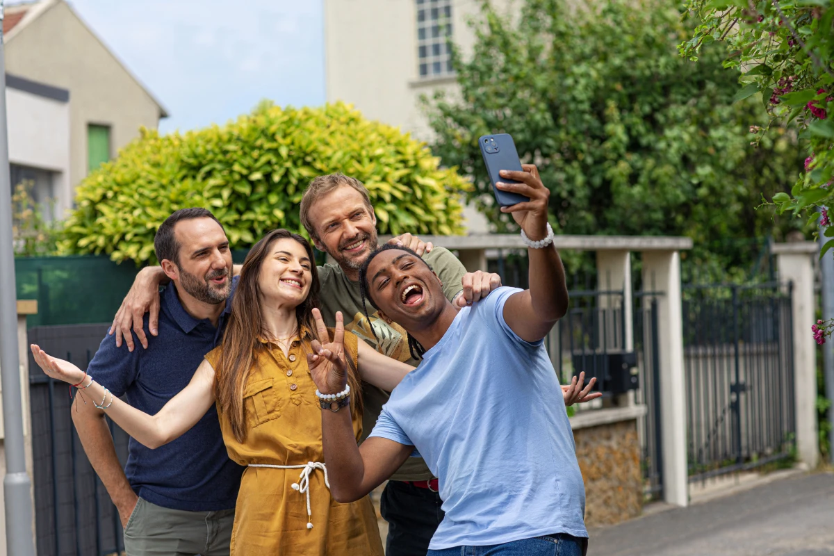 Groupe d’amis souriants devant leur smartphone, ils profitent du réseau Bouygues Telecom