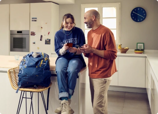 Un homme et une femme sur un comptoir de cuisine, partageant un moment en consultant un téléphone.