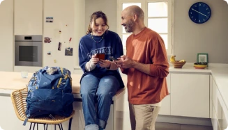 Un homme et une femme sur un comptoir de cuisine, partageant un moment en consultant un téléphone.