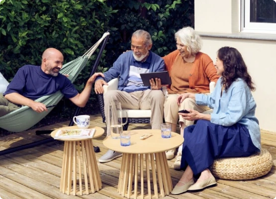 Un groupe de quatre amis sur un deck, profitant d'une tablette, tandis qu'un hamac les invite à se reposer.